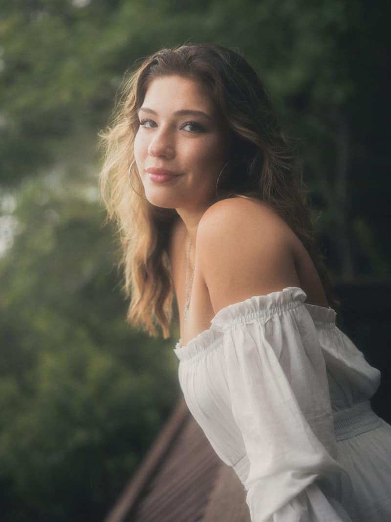 Golden light portrait leaning on a lakeside railing