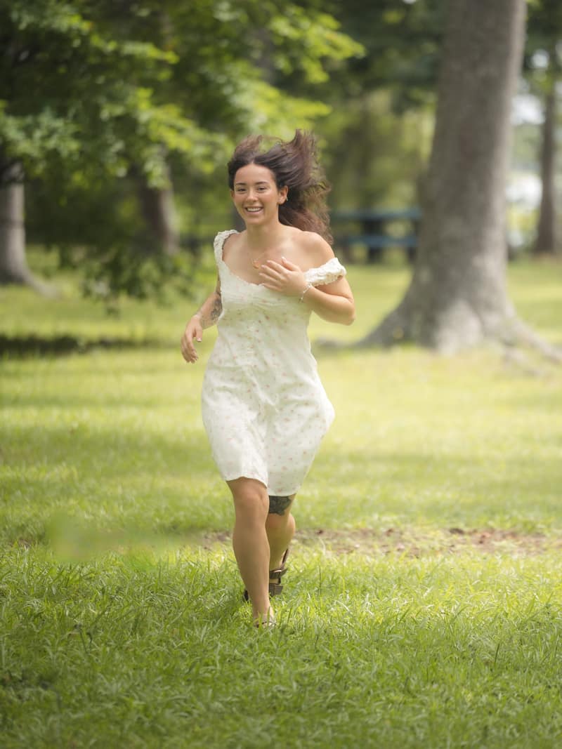 Running through a park laughing, hair flying