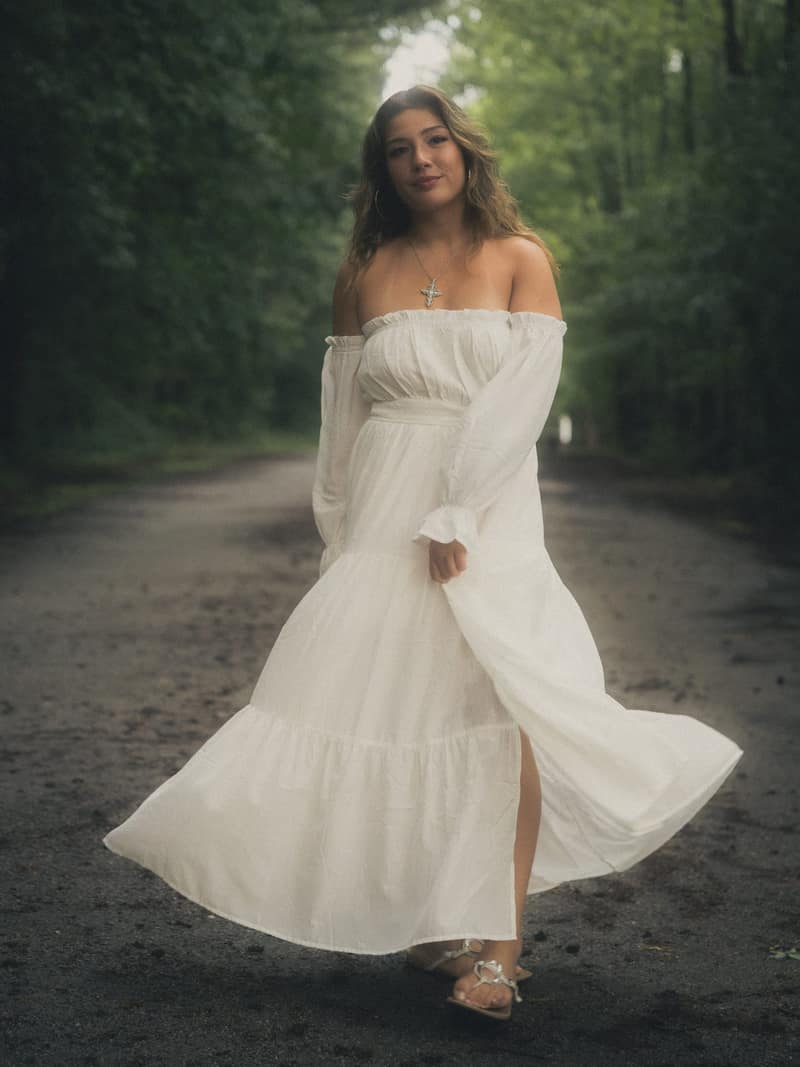 Full-length white dress on a dark forest road