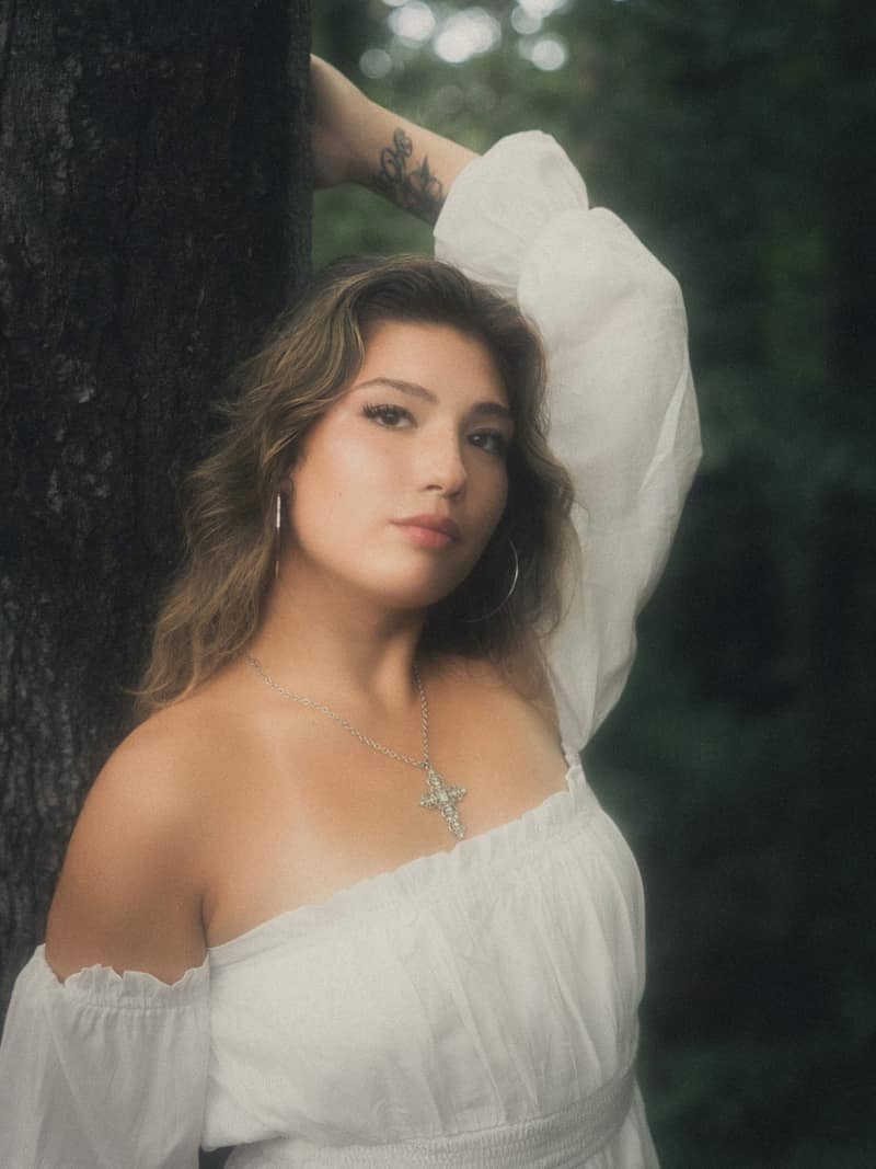 Close portrait against a tree, arm overhead