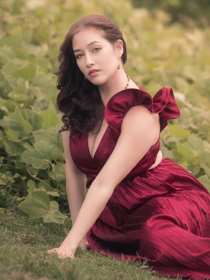 Seated in a kudzu meadow in a wine satin gown