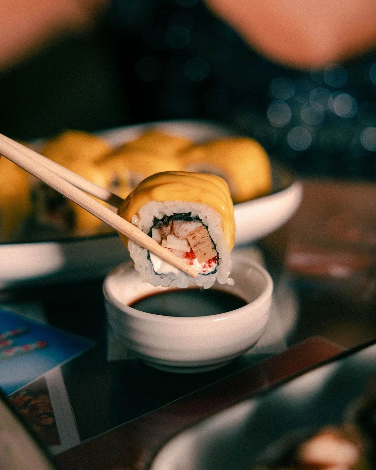 Close-up of a sushi roll held above a dipping bowl · Friends Sushi
