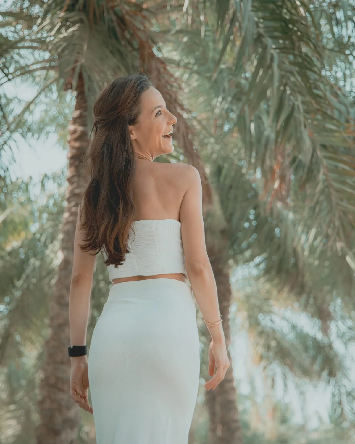 Guest in a light dress beneath palm trees · Royal Saray and Palavra